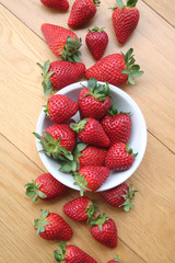 Fresh strawberries in a bowl on wooden background