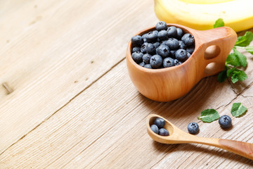 Blueberries in wooden mug Kuksa is Ancient Lapland Finland Wooden Drinking Cup on old wooden table, close-up