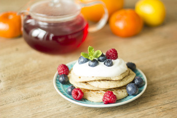 Homemade pancakes with fruits and fresh oranges and lemons on the background