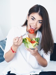 Asian woman eating vegetables salad in the morning.