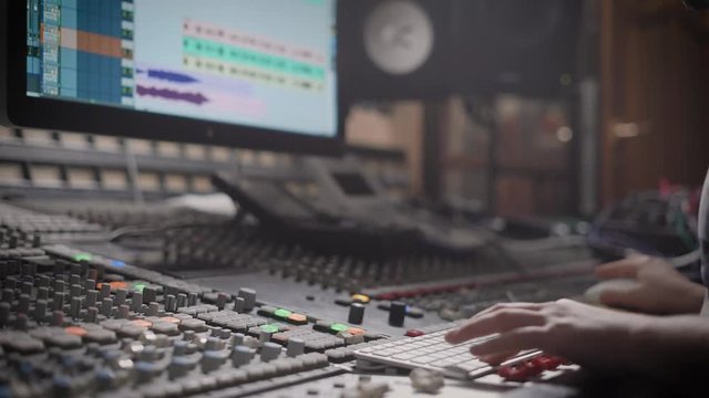 close up shot of the recording engineer, who mixes the tracks in his office, the man holds his hands on a professional mixer