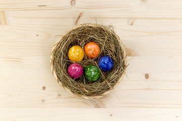 Korb mit Heu und bunten Eiern auf Holz aus Fichte