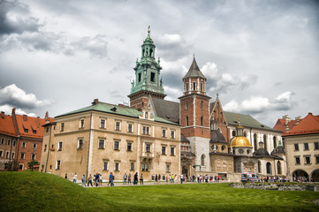 Fototapeta na wymiar Krakow, Poland - June 04, 2017: Wawel cathedral with chapels on green hill. Tourists at catholic church on cloudy sky. Architecture and design. Travelling, vacation and wanderlust