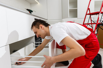 Obraz premium Handyman putting up a shelf in the kitchen