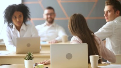 Young excited employee looking at laptop screen with surprise, gossip girl sharing good funny news with coworkers, spreading rumors in coworking office, colleagues talking at workplace, word of mouth
