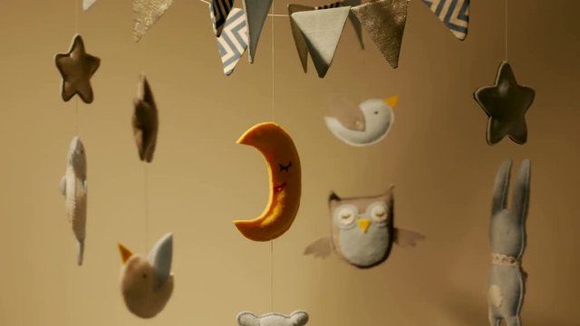 baby mobile with blue hand-stitched animal and bird toys with yellow moon on white wall background