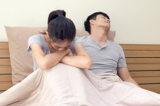 Couple relationship concepts. Young asian man sad after have an argument with his girlfriend on bed. woman is crying on the bed.