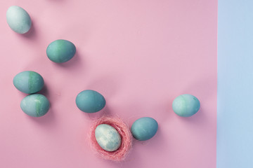 Obraz premium Several different shades blue eggs and blue egg decorated with pink sisal nest on the geometric pink and blue background.