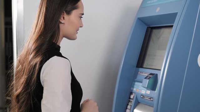 young woman inserting a credit card to ATM, beautiful girl banking contactless nfc in shopping mall airport terminal office