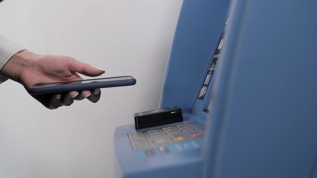 withdrawing money from atm with a mobile phone a NFC terminal office shopping mall terminal airport close up