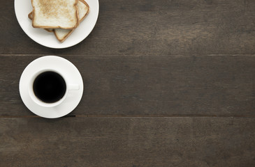 Black coffee in white cup and toast on white dish retro style on wooden background copyspace flatlay.