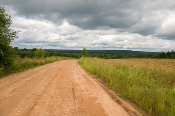 Fototapeta premium Country road in bad weather descends from a height