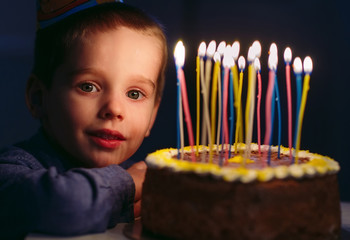 Birthday. A little boy blows out candles on the stoke.