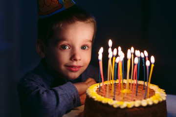 Birthday. A little boy blows out candles on the stoke.