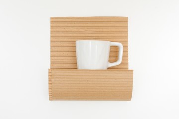 White cup in kraft paper on white background. Concept of storage, feeling safe, protect, relocation.