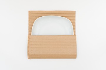  White plate in kraft paper on white background. Concept of storage, feeling safe, protect, relocation.
