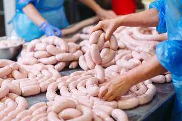 Fototapeta premium Butchers processing sausages at meat factory.
