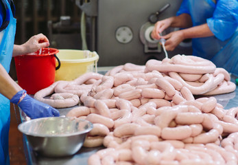 Butchers processing sausages at meat factory.