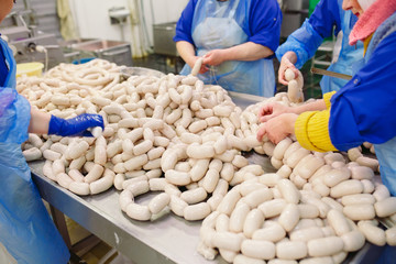 Butchers processing sausages at meat factory.