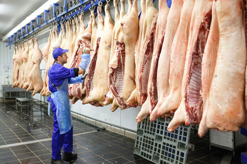 Butcher cutting pork  at the meat manufacturing.