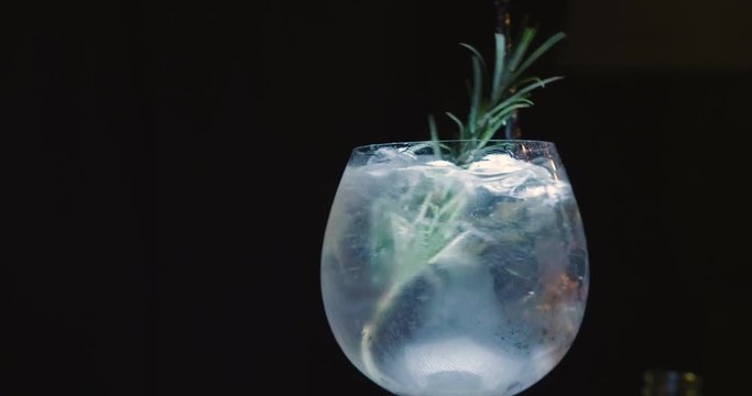in a nightclub or pub, a professional bartender preparing a cocktail with ice a mix of alcohol. The barman measure quantities for a perfect cocktail. concept: disco, fun, friends, cocktail.