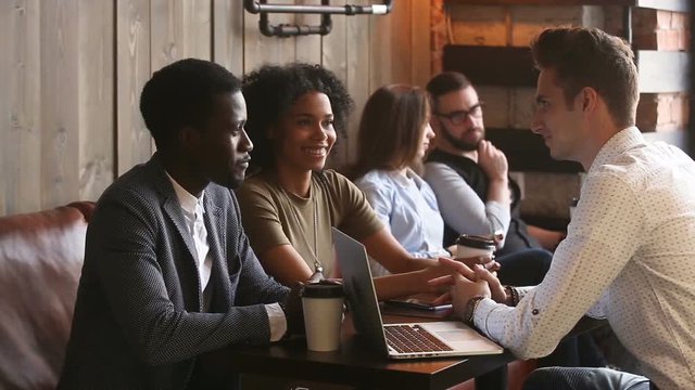 Black couple talking agreeing with white businessman making offer in coffee house, financial advisor or lawyer consulting african family with laptop, diverse people negotiating at meeting in cafe