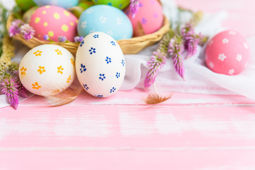 Obraz na płótnie Canvas Happy easter! Colorful of Easter eggs in nest with paper star, flower and Feather on pastel color bright pink and white wooden background.