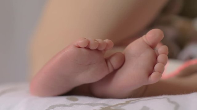 Close-up shot of baby slightly moving her little feet when sleeping or breastfeeding