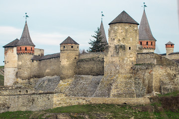 Fototapeta na wymiar Kamianets Podilskyi fortress built in the 14th century. View of the fortress wall with towers at early springtime, Ukraine