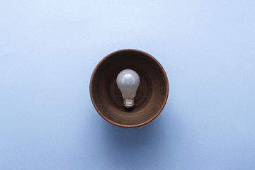 Creative idea - light bulb in brown plate on pastel blue background