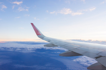 Obraz premium Wing of airplane flying above clouds in the sky.