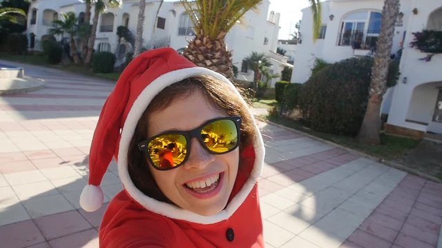 Happy young woman in santa hat taking selfie