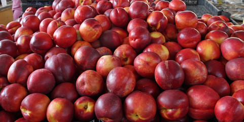Peaches. Big pile of nectarines on an market, fruits background. Peach and nectarine texture pattern. Healthy food. Fresh organic peaches. 