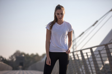 Sports woman in a white T-shirt while training on the bridge. Mock-up.