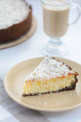 slice of a cheesecake with a cup of coffee on a white background