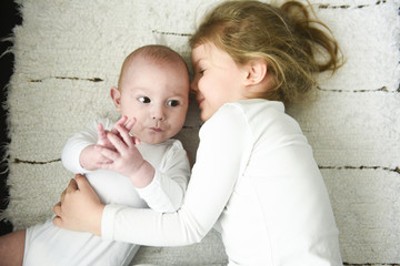 sister girl hugs newborn brother