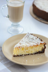 slice of a cheesecake with a cup of coffee on a white background
