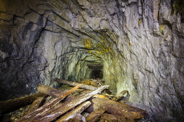 Underground abandoned gold ore mine shaft tunnel gallery with wooden timber