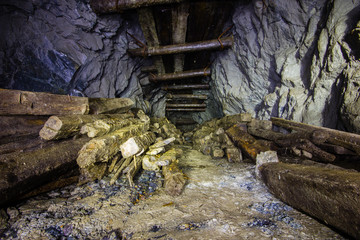 Underground abandoned gold ore mine shaft tunnel gallery with wooden timber