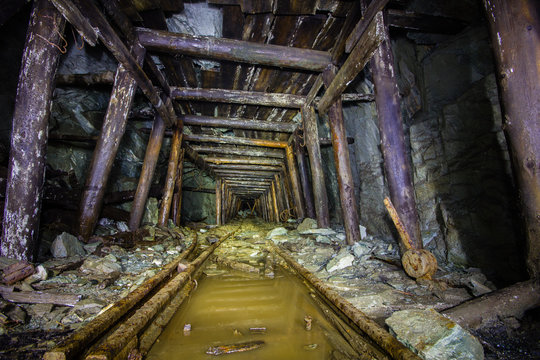 Underground abandoned gold ore mine shaft tunnel gallery with wooden timber