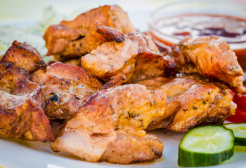 Juicy kebab on a plate with a sliced cucumber