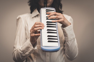 Someone is playing a melodica, also known as blow-organ, in vertical position. The hands are...