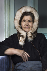 Portrait of an elderly woman in fur winter hat. The inhabitants of the north.