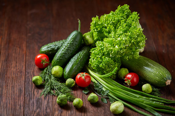 Vegetarian still life of fresh vegetables on wooden plate over rustic background, close-up, flat lay.