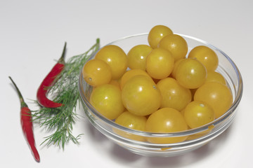 Raw yellow cherry tomatoes in the glass dish closeup, ready to eat, isolated on white, vegan food.