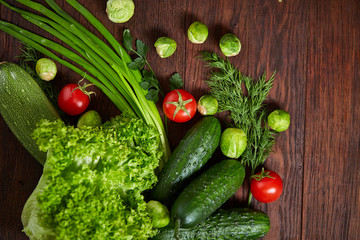Vegetarian still life of fresh vegetables on wooden plate over rustic background, close-up, flat lay.