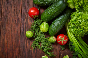 Vegetarian still life of fresh vegetables on wooden plate over rustic background, close-up, flat lay.