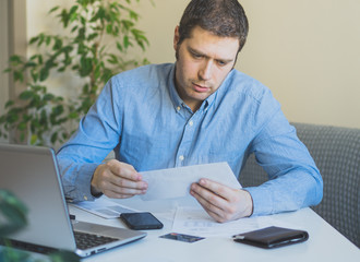 Man looking at his monthly bills at home.