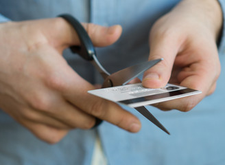 Man cutting credit card with scissors.