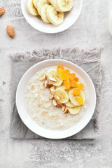 Oats porridge with banana slices, nuts and dried apricot